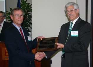Alex Barbarika (left) receives the prestigious Fred Woods Economic Policy Award for his continuous reporting of Conservation Reserve Program information. Presenting him the award is EPAS colleague Skip Hyberg. They were joined by USDA Secretary Tom Vilsack at the presentation. 