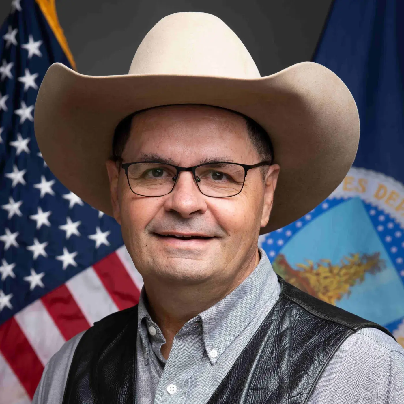 Headshot of Zach Ducheneaux with flags in the background